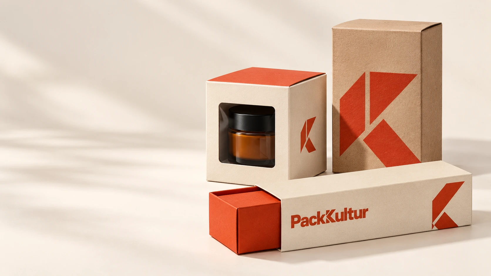 Cremefarbene Produktschachtel mit Sichtfenster, Kraftkarton und zinnoberroter Schuber mit PackKultur-Druck